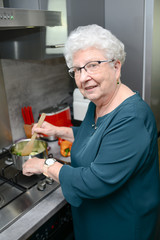 happy senior active woman cooking at home in a modern kitchen