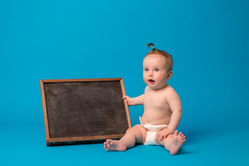 baby sitting and holding a chalkboard,Baby happy on the blue background, new family and love concept , copy space