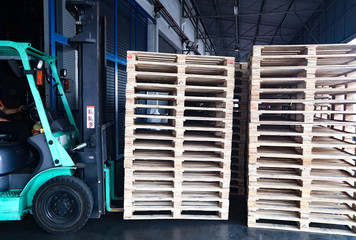 The forklift and wooden pallets heap in the cargo warehouse for transportation and logistics 