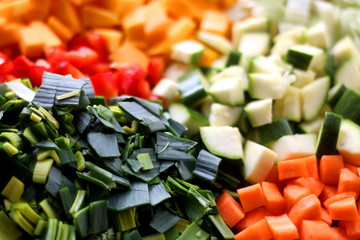 Various chopped vegetables: butternut squash, cabbage, red pepper, courgette, leek and carrot. Top view, selective focus.