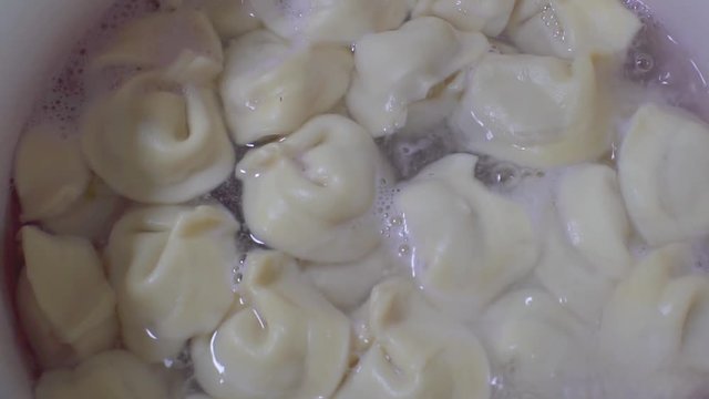 Dumplings are boiled in a saucepan on a gas stove. Cooking dumplings in slow motion.
