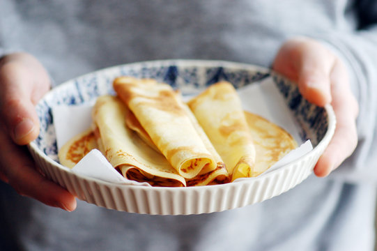 Woman's hands holding dish with homemade crepes