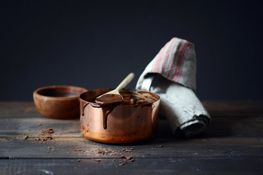 Chocolate sauce on spoon and copper pot