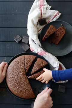 Child's hand grabs a slice of chocolate cake