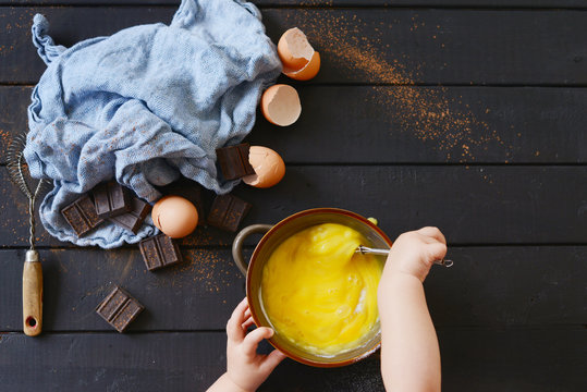 Child's hands mixing eggs in copper bowl