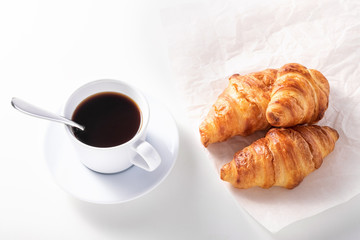 cup of black coffee and croissant on white