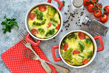 Casserole with broccoli and tomatoes on a concrete background. View from above.
