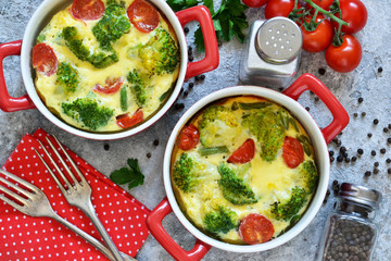 Casserole with broccoli and tomatoes on a concrete background. View from above.