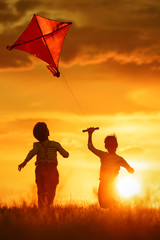 Children with a kite at sunset