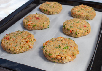 Row of best fish cakes raw uncooked on  baking tray.