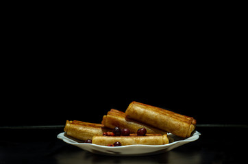fried pancakes. stuffed pancakes. wrapped pancakes on a white plate with berries