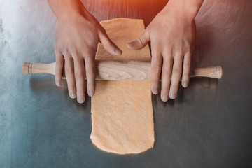 human hands unrolling dough;