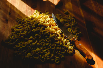 Orecchiette, Italian wheat semolina pasta, on a table and a knife.