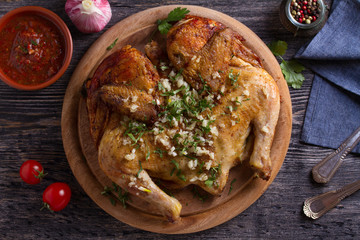 Roasted chicken with garlic on wooden tray. View from above, top