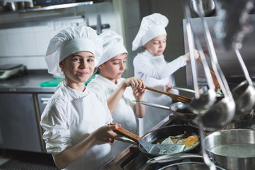 Children cook eggs in the kitchen at the Restaurant.
