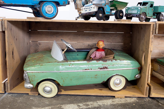 Old vintage toy car with doll in a wooden box.