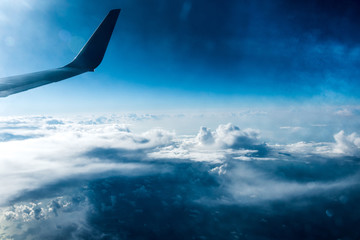 View from the plane, with the wing, on top of white clouds above the water