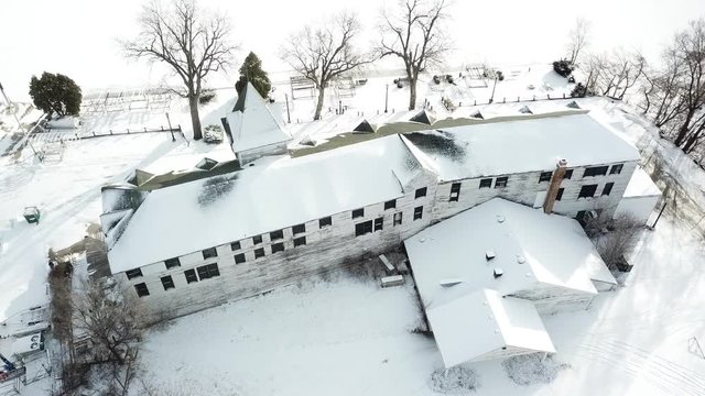 AERIAL: lowering and tilting up from behind The Mineola Hotel in Fox Lake, Illinois to reveal the froze lake in the background.