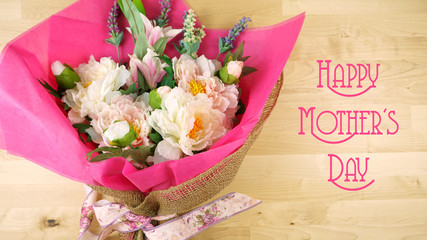Flowers wrapped in pink tissue and hessian modern trend wrapping flat lay for Mother's Day, birthday or Valentine's Day, with text greeting.