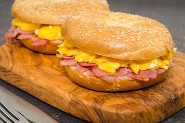Breakfast sandwich bagel with egg and bacon, close-up view.