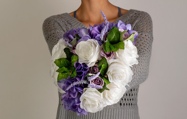 Close Up of Girl Holding Bouquet of Purple and White Flowers on a Gray Backdrop © Duvy  Photography
