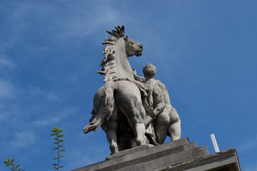 Rear view of statue of horse and man - naked against blue sky