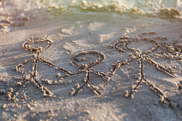 Family drawn in the sand. Three people - father, mother and child are depicted on the shore.