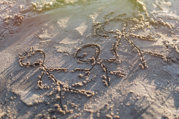 Family drawn in the sand. Three people - father, mother and child are depicted on the shore.