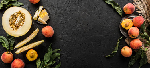 Melon and peaches. Creative layout made of fruits. Colorful fresh fruit on black stone background. Top view, flat lay
