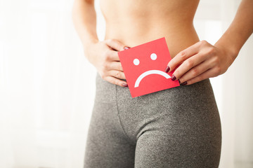 Vaginal or urinary infection and problems concept. Young woman holds paper with sad smile above...