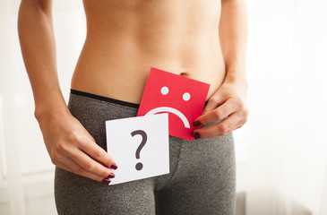 Vaginal or urinary infection and problems concept. Young woman holds paper with sad smile above...