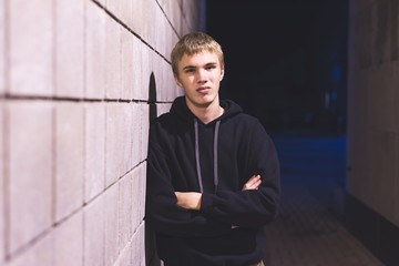 Upset teenager leaning against a brick wall in an alleyway. He is suffering from depression.