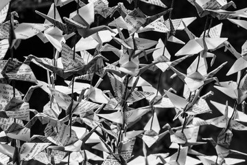 Black and white close view of folded paper origami cranes strung together, horizontal aspect