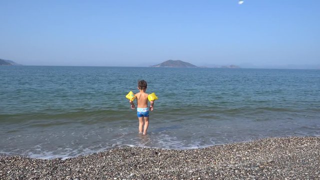 4K Kid with safety arm rings enters the cold sea