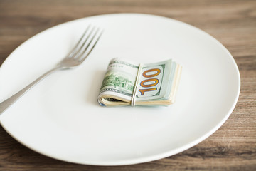 Money lying on the plate with fork. Dollars photo. Greedy corruption concept. Bribe idea