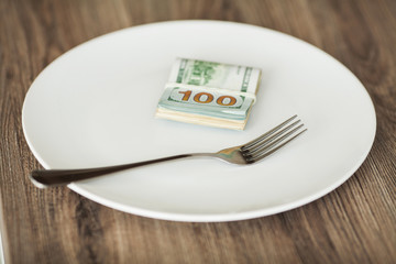 Money lying on the plate with fork. Dollars photo. Greedy corruption concept. Bribe idea