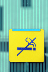 Yellow no smoking sign on green glass wall