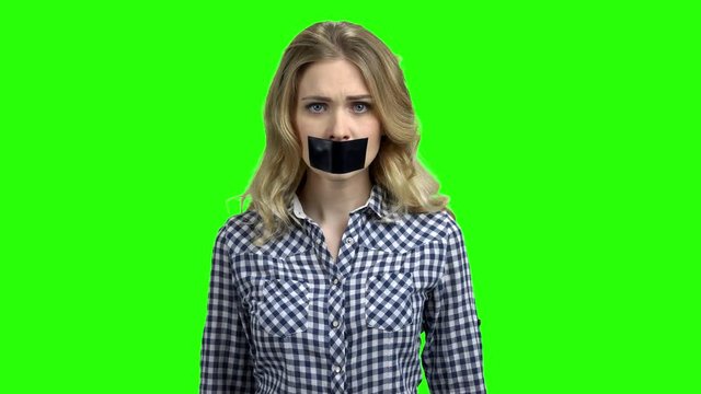 Caucasian woman with mouth covered with tape. Female protestor with black tape over her mouth demonstrating protest on green screen. Concept of forbidden opinion.