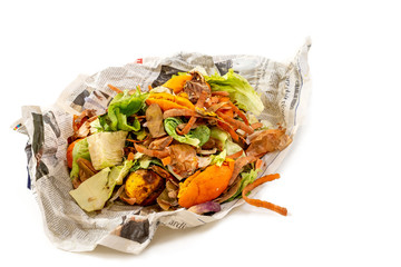 A pile of food waste, such as eggshells and fruit and vegetable peels, on a newspaper white...