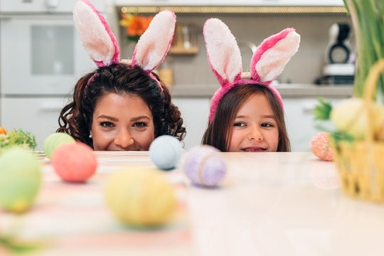 Mother and her cute little daughter having fun in kitchen while preparing Easter eggs.