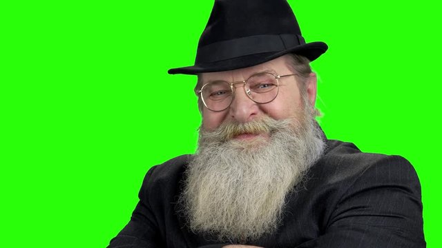 Close up old bearded man looking at camera. Face of senior bearded man wearing eyeglasses on green screen.