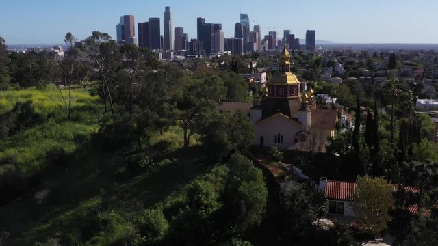 Drone flys around sunny park in East Los Angeles showing greenery and grass.