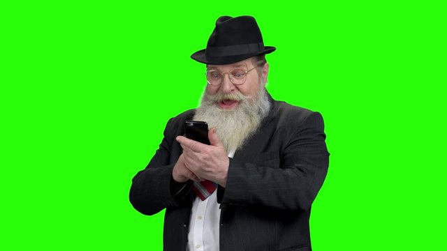 Senior bearded man taking photo with phone. Old caucasian man using phone on Chroma Key background. Seniors and modern technology.