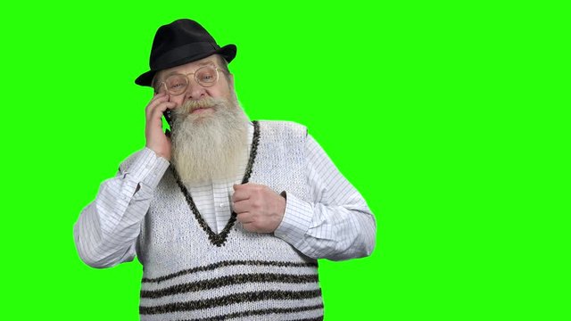 Serious old man talking on cell phone. Aged business man with long beard using mobile phone on Chroma Key background.