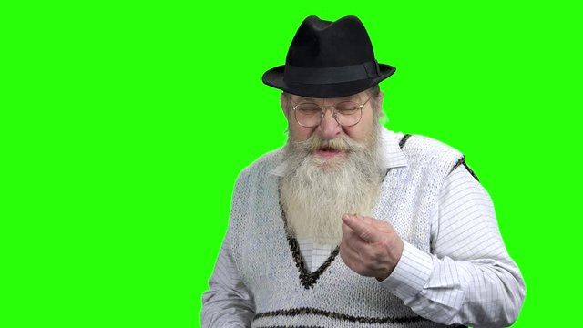 Displeased senior man talking to someone on green screen. Dissatisfied elderly man arguing with someone. Dispute concept.