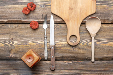 utensils with square candle and vintage cutlery on wooden background, top view 