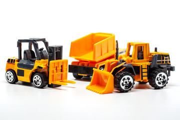 Obraz na płótnie Canvas A yellow toy heavy machinery includes dump truck, bulldozer and forklift on white background for vehicle and transportation concept