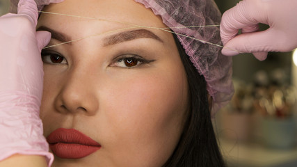Microbleeding and eyebrow architecture. Beautician checks correctness of shape of eyebrows on...