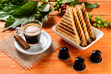 Glass of clear glass of hot coffee on wooden table. Orange wood pinus.