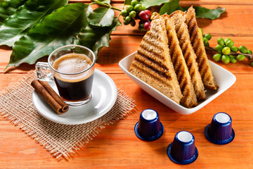 Glass of clear glass of hot coffee on wooden table. Orange wood pinus.